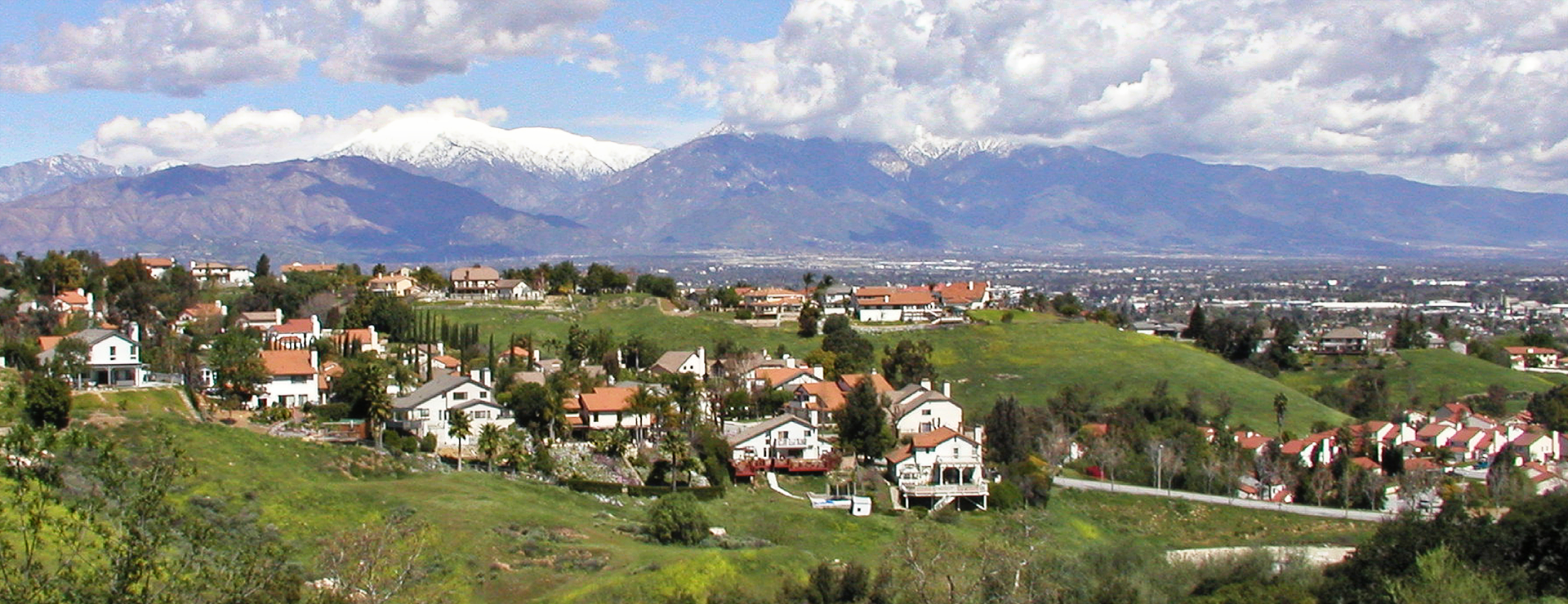 Hillside residential area with scattered houses, green fields, and mountain backdrop in Chino Hills.