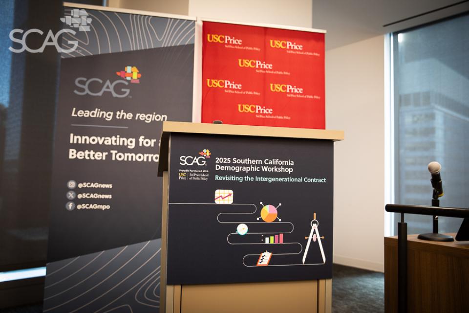 Conference podium with SCAG and USC banners, microphone on the right.