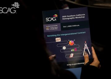 Hands holding a SCAG workshop flyer in a dim setting.