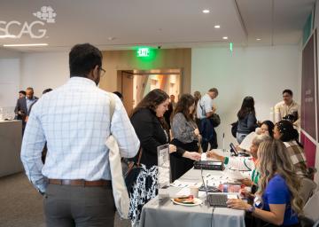 People interacting at a conference registration desk.
