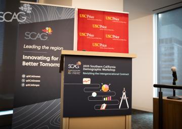 Conference podium with SCAG and USC banners, microphone on the right.