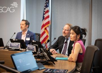 Panelists at a conference table with an American flag in the background.