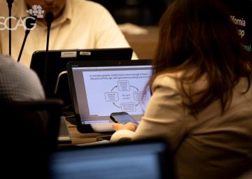 Person viewing a presentation on a laptop in a conference setting.