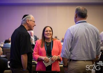 Three people talking and smiling in a conference room.