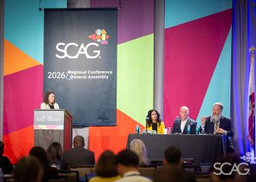 Panelists on stage at a colorful conference backdrop with SCAG logo.