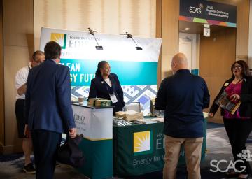 Trade show booth with people interacting, branded "Edison," bright lighting.
