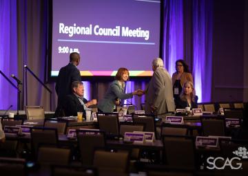 People conversing at a meeting in a purple-lit conference room.