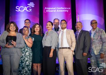 Diverse group posing at conference with purple backdrop.