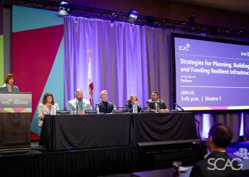 Panel of six people at a conference with purple-lit stage.