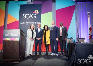Five people posing in front of a colorful stage backdrop at a conference.