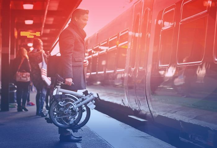 Man holding folding bike waiting for a train